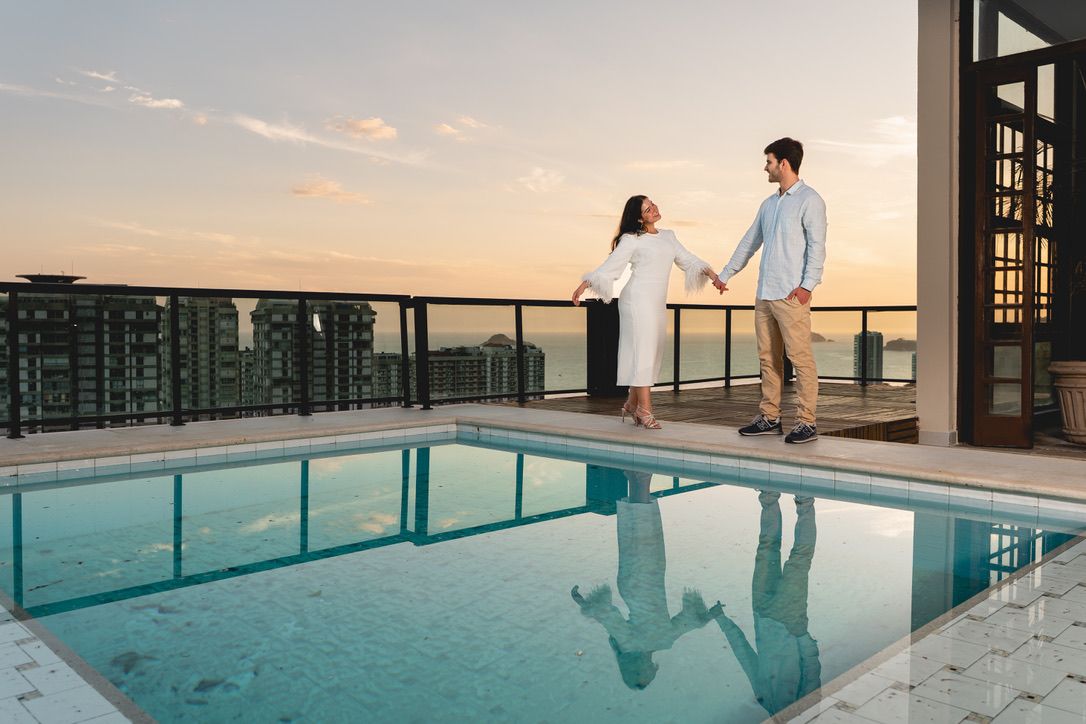 Maria Isabella e Eric de mãos dadas junto à piscina ao pôr do sol